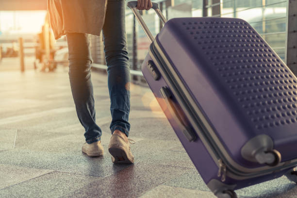 Traveler with suitcase in airport concept.Young girl walking with carrying luggage and passenger for tour travel booking ticket flight at international vacation time in holiday rest and relaxation.